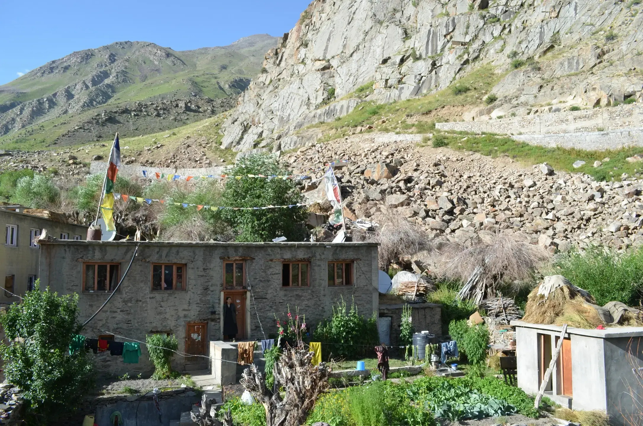 Rooftops stacked with hay below a peak in Lahaul